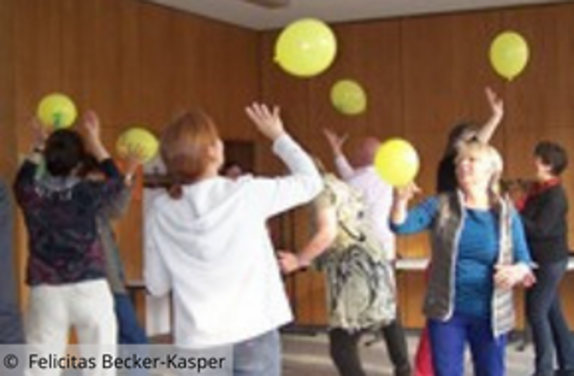 Gruppe spielt in einem Raum mit gelben Ballons
