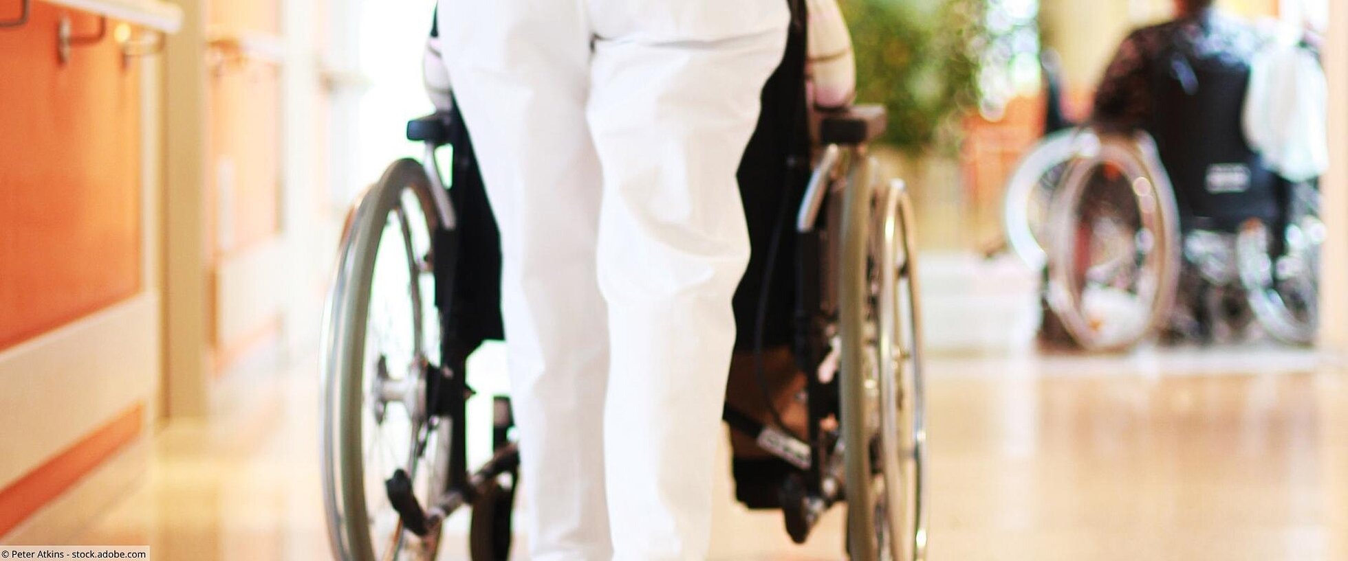 Pflegerin schiebt Rollstuhl