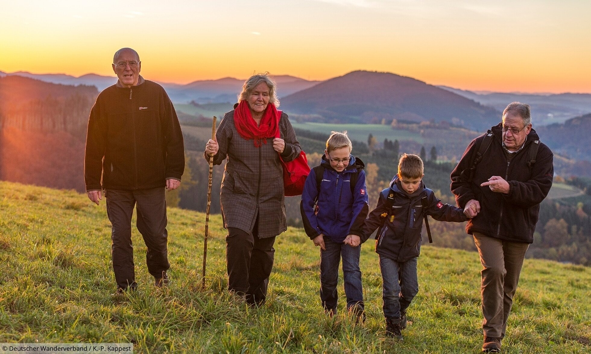 Familie wandert über einen Hügel bei Sonnenuntergang