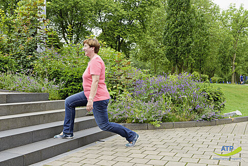 Ältere Frau macht einen Ausfallschritt an einer Treppe