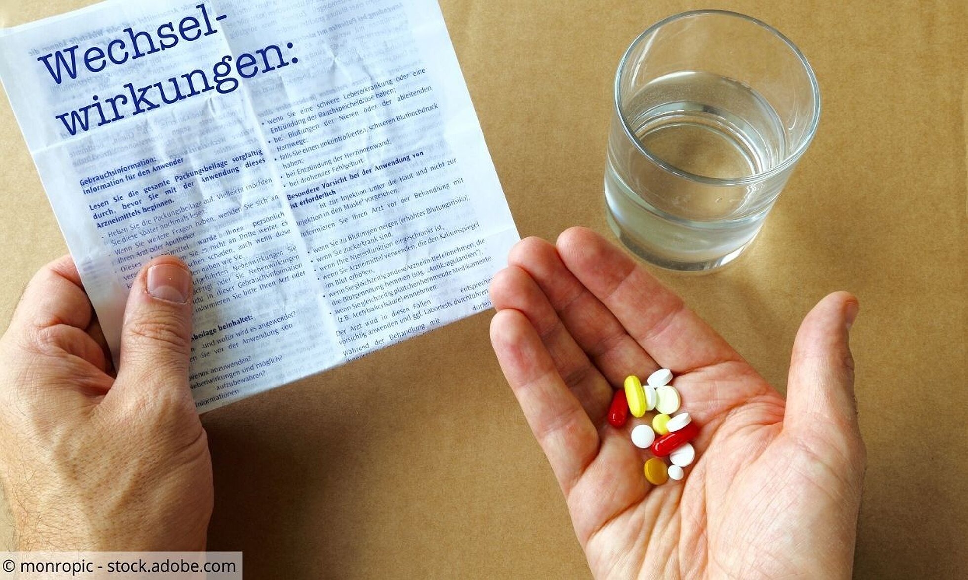 Hand mit Tabletten und Infoblatt zu Wechselwirkungen