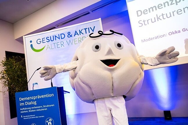 Bundeskonferenz Gesundes Alter 2026: Konferenzmaskottchen auf der Bühne