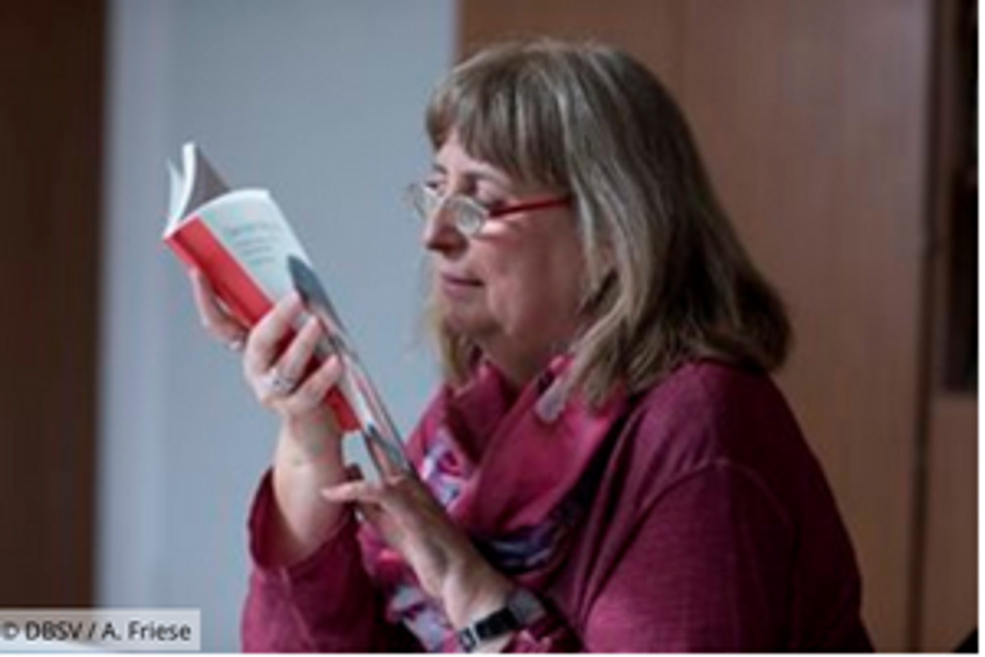 Ältere Frau mit Lupenbrille liest ein Buch