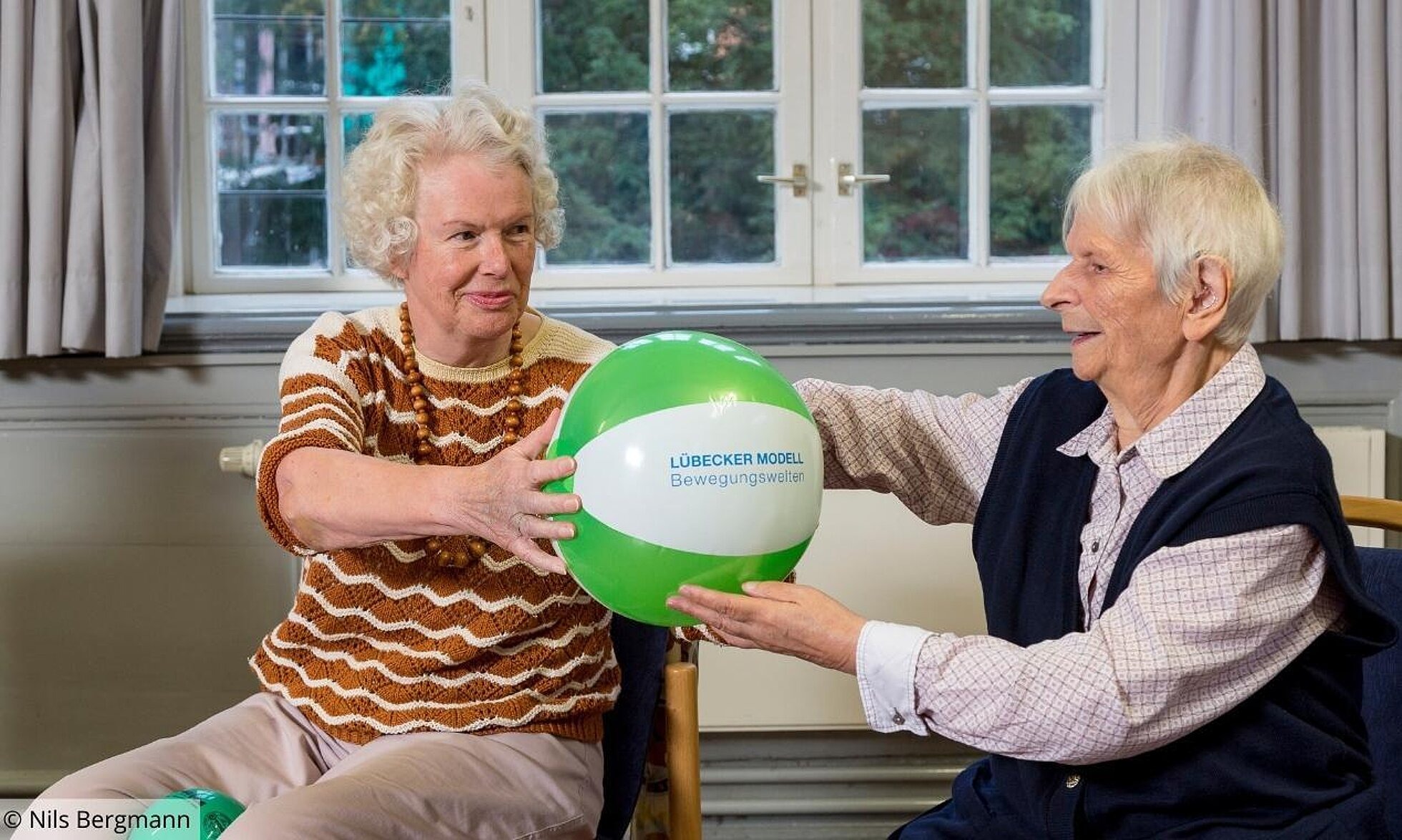 2 ältere Frauen reichen sich einen aufblasbaren Ball