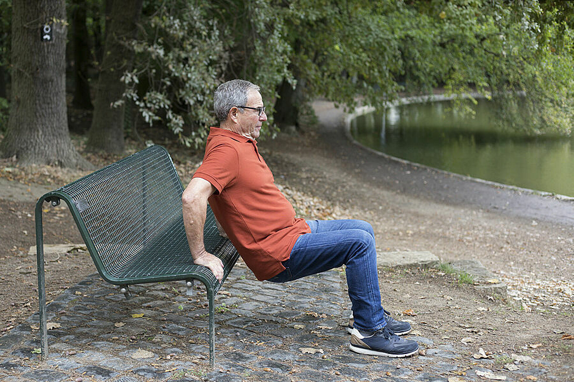 Man macht Stützbeugen mithilfe einer Parkbank