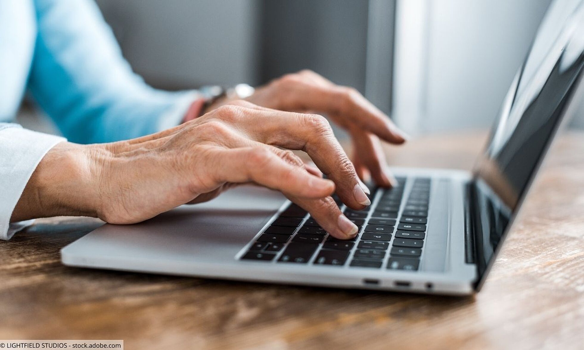 Nebenwirkungen von Medikamenten melden Hände einer Seniorin tippen auf Laptoptastatur