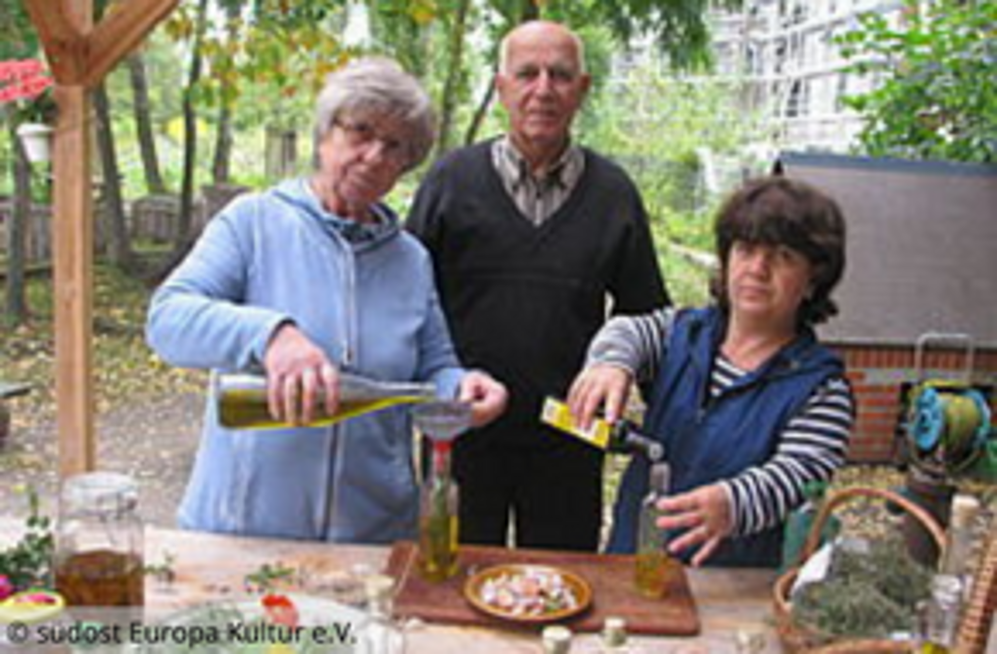 Gruppenbild: 3 Personen im Garten am Tisch