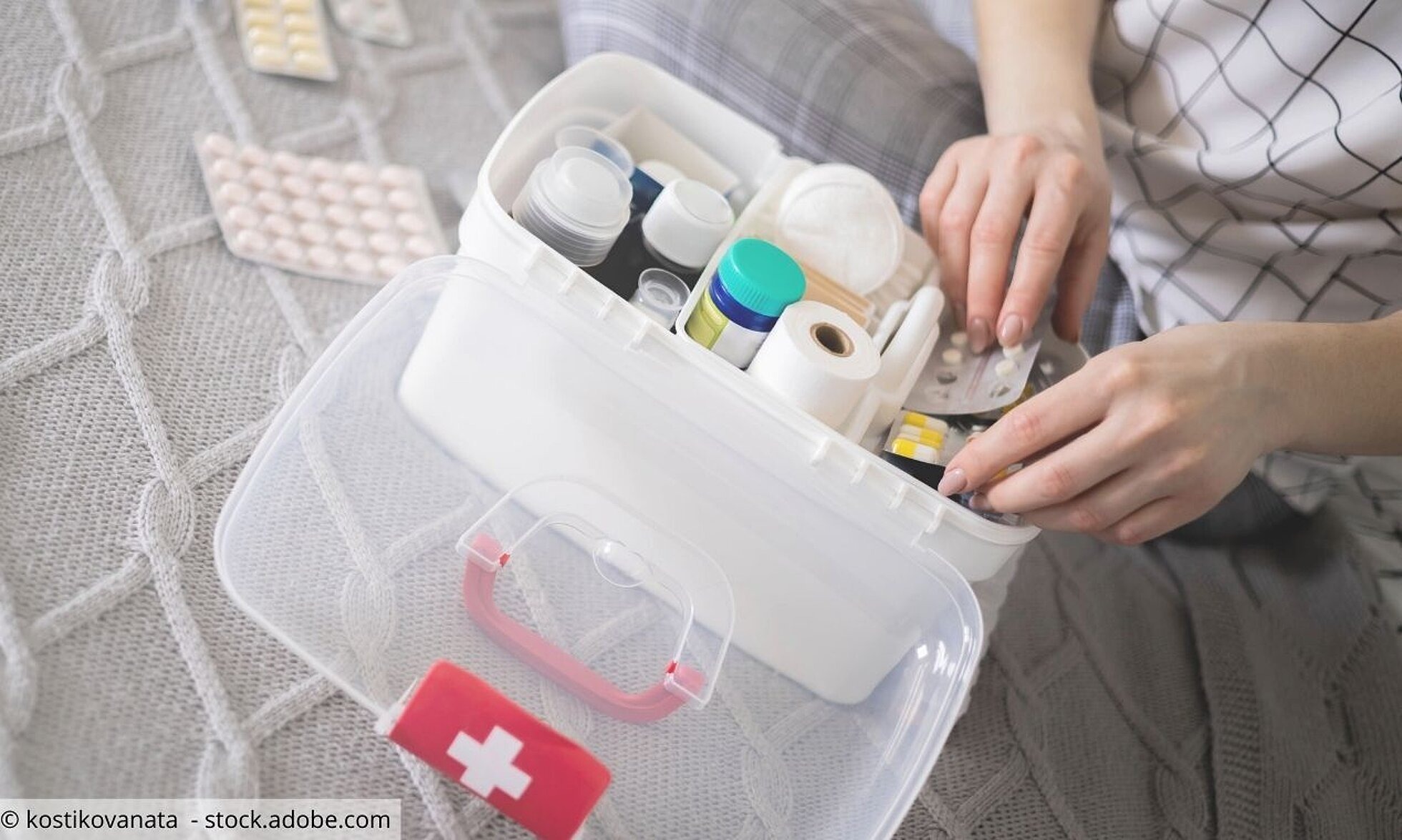 Frau sortiert Tabletten, Salben, Verbandszeug in Erste-Hilfe-Box