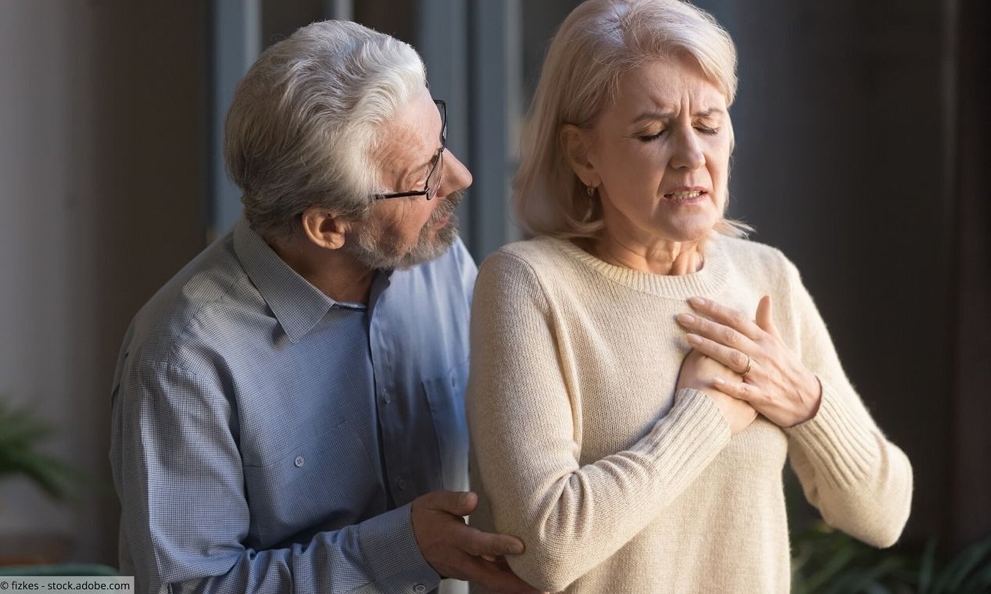 Ältere Frau mit Herzbeschwerden, älterer Mann besorgt