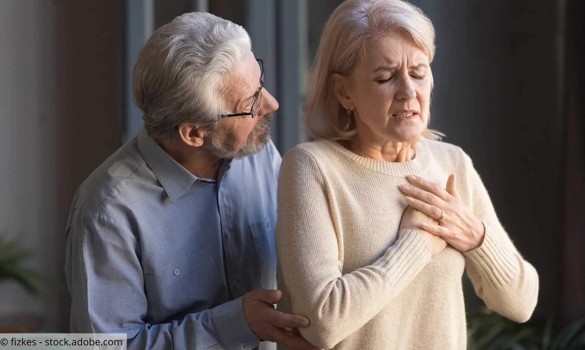 Ältere Frau mit Herzbeschwerden, älterer Mann besorgt