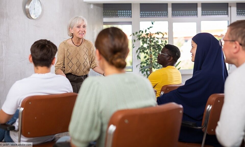 Ältere Kursleiterin vor einer Schulungsgruppe