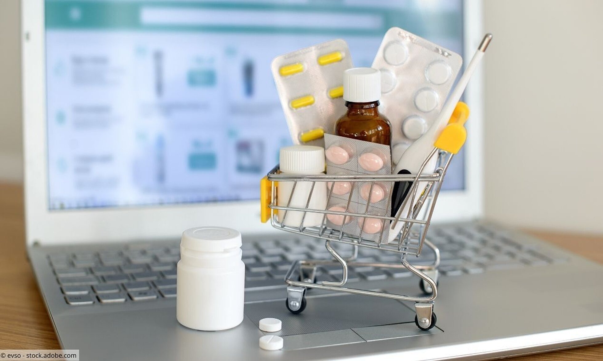 Kleiner Einkaufswagen mit Tabletten steht auf Laptop