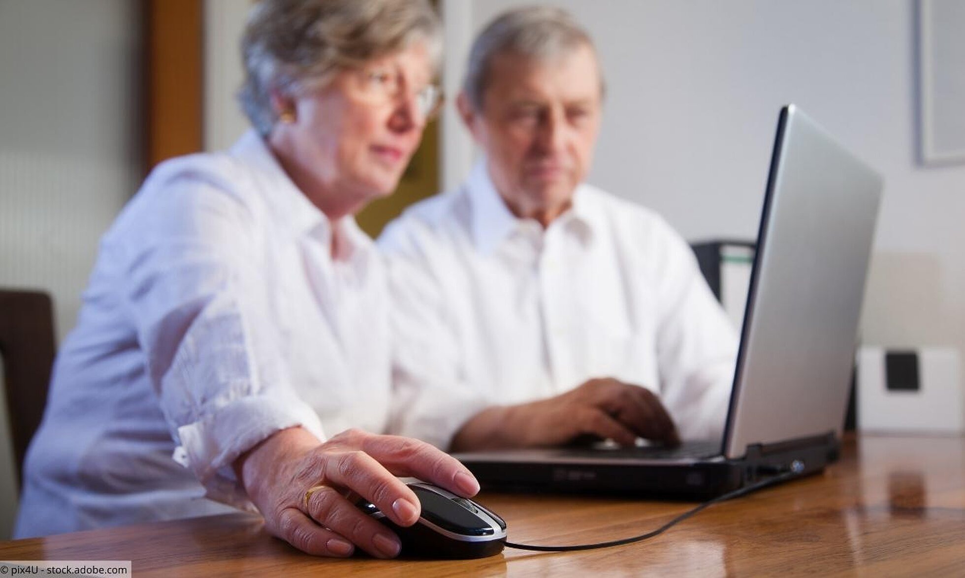 BZgA-Shop Seniorin und Senior mit einem Laptop bestellen im Internet.