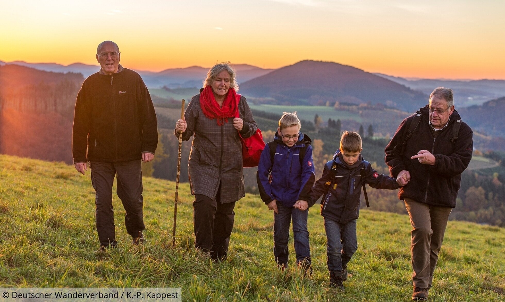 Familie wandert über einen Hügel bei Sonnenuntergang