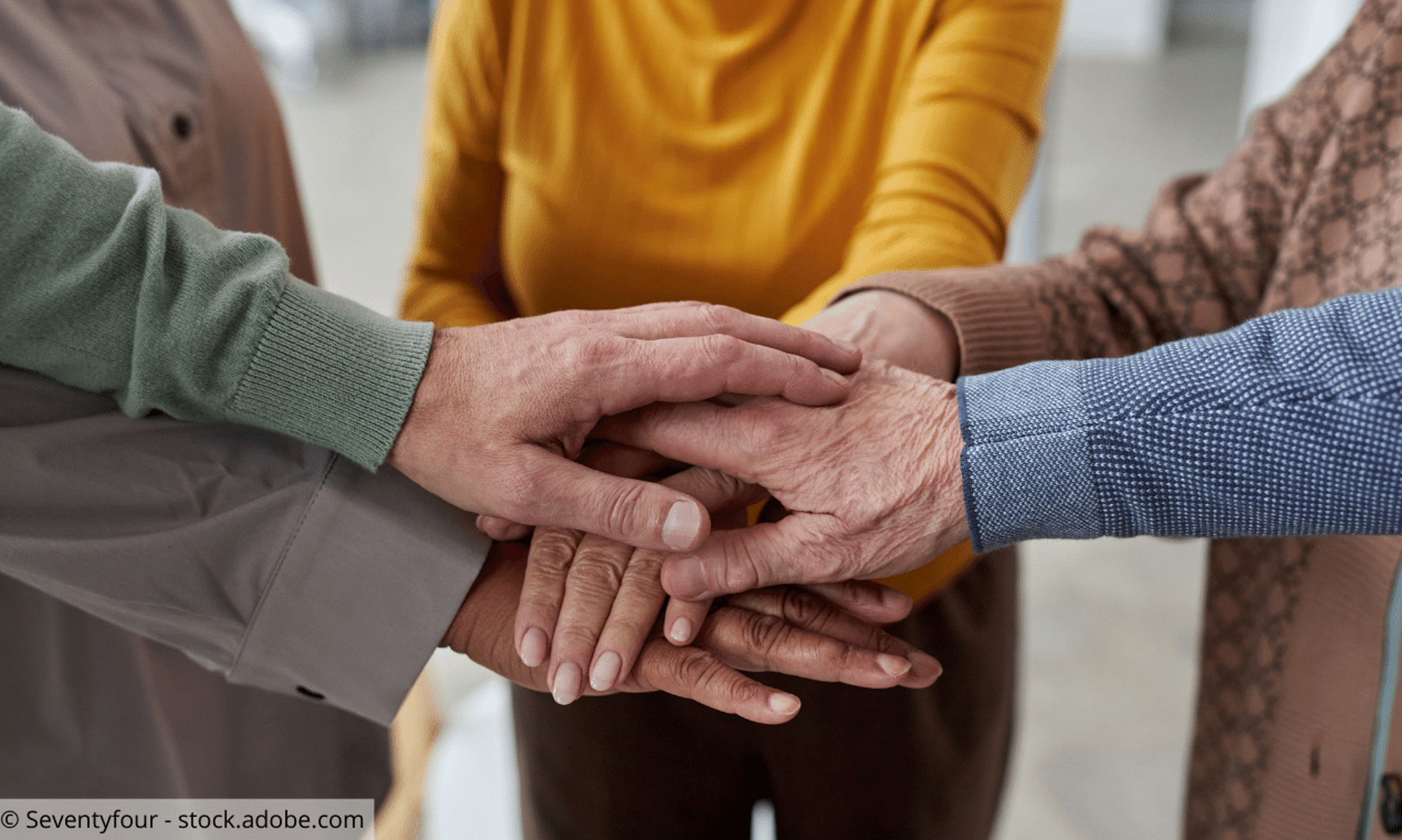 Seniorinnen und Senioren legen Hände aufeinander