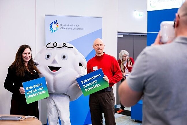 Bundeskonferenz Gesundes Alter 2026: Teilnehmende mit Maskottchen