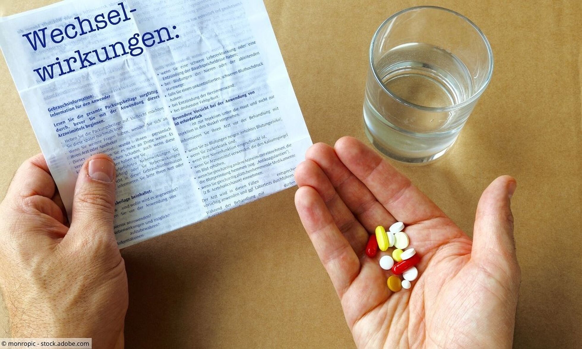Hand mit Tabletten und Infoblatt zu Wechselwirkungen