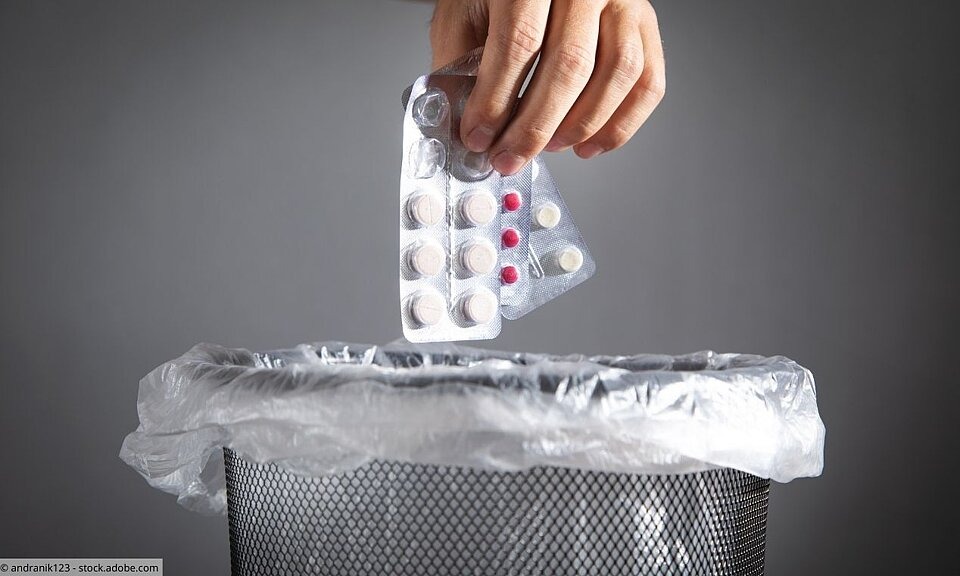 Hand wirft Tabletten in Abfalleimer