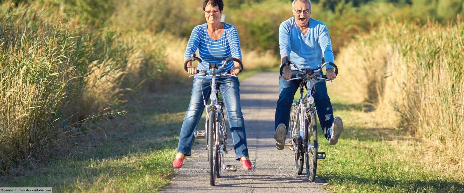 Eine ältere Frau und ein älterer Mann fahren Fahrrad auf einem Feldweg